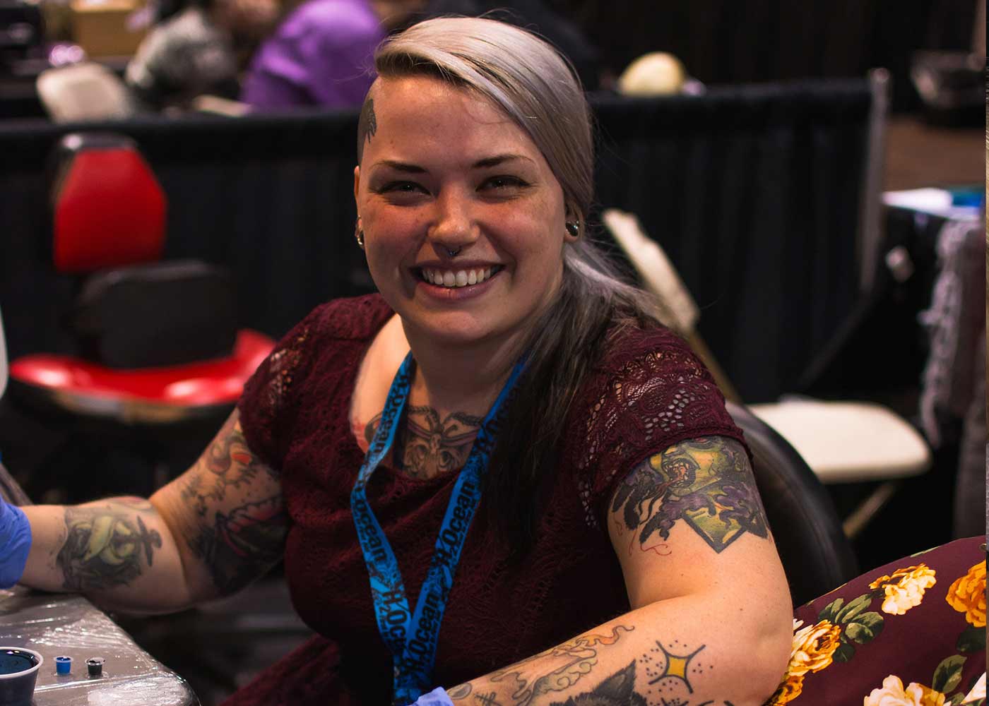 Smiling tattoo artist with inked arms and badge