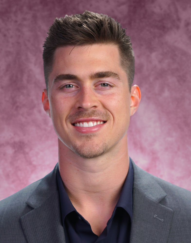 Smiling man in suit with pink background.