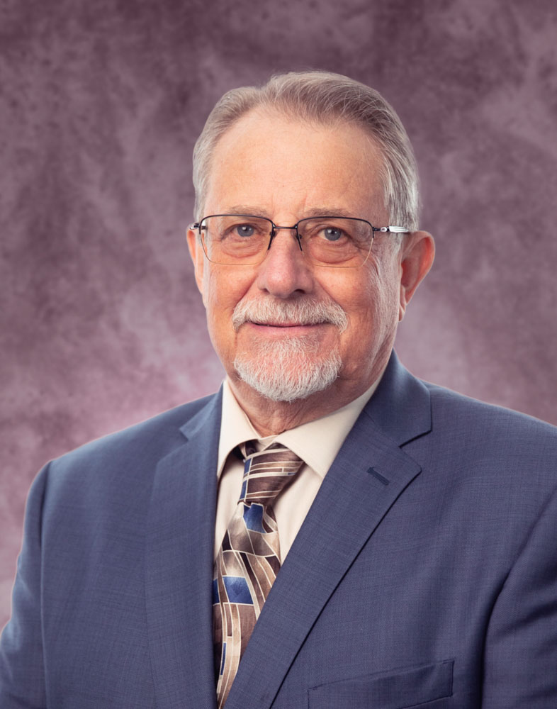Elderly man in suit with glasses and beard.