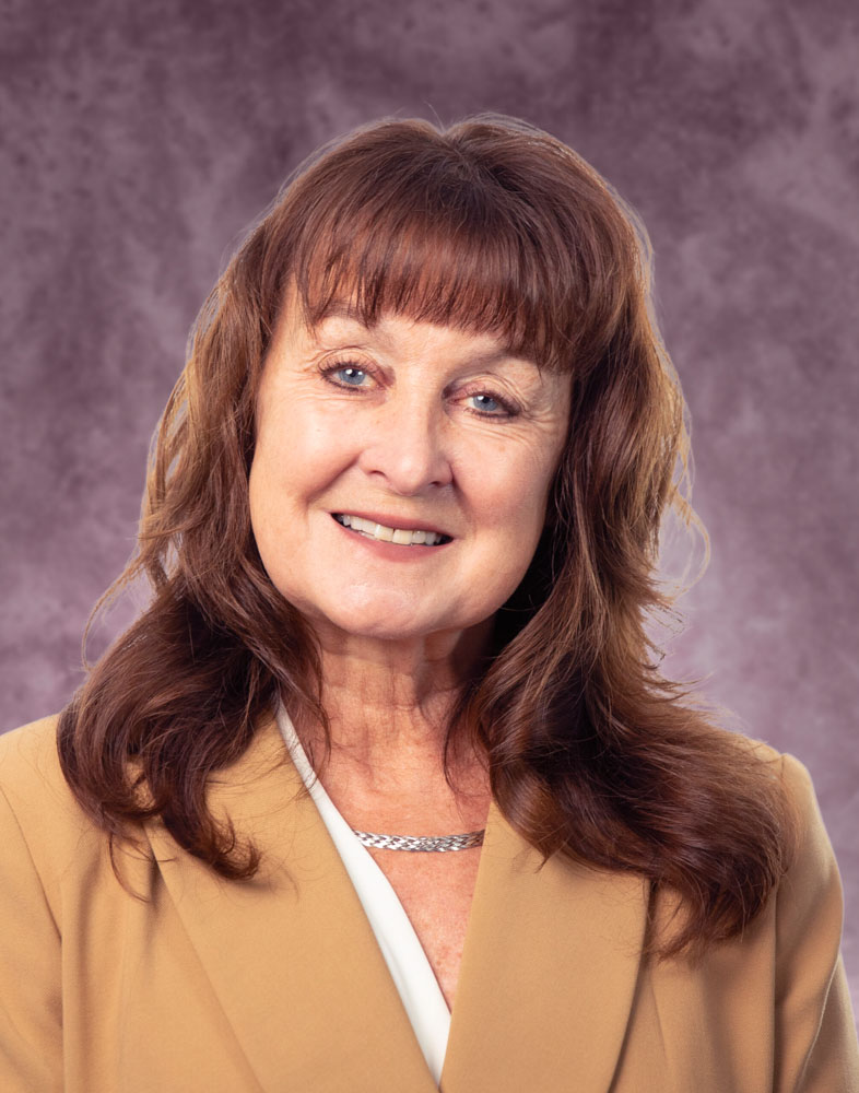 Smiling woman in beige blazer portrait.