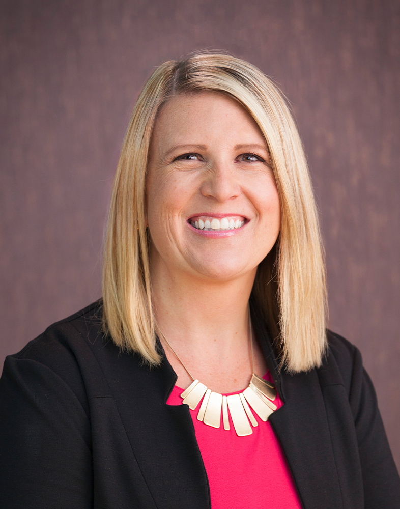Smiling woman with blonde hair and necklace.