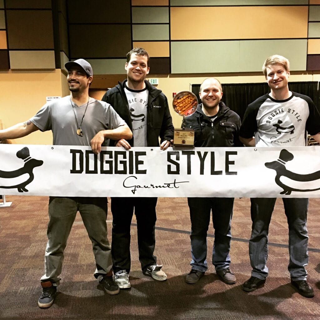 Four men holding Doggie Style banner.