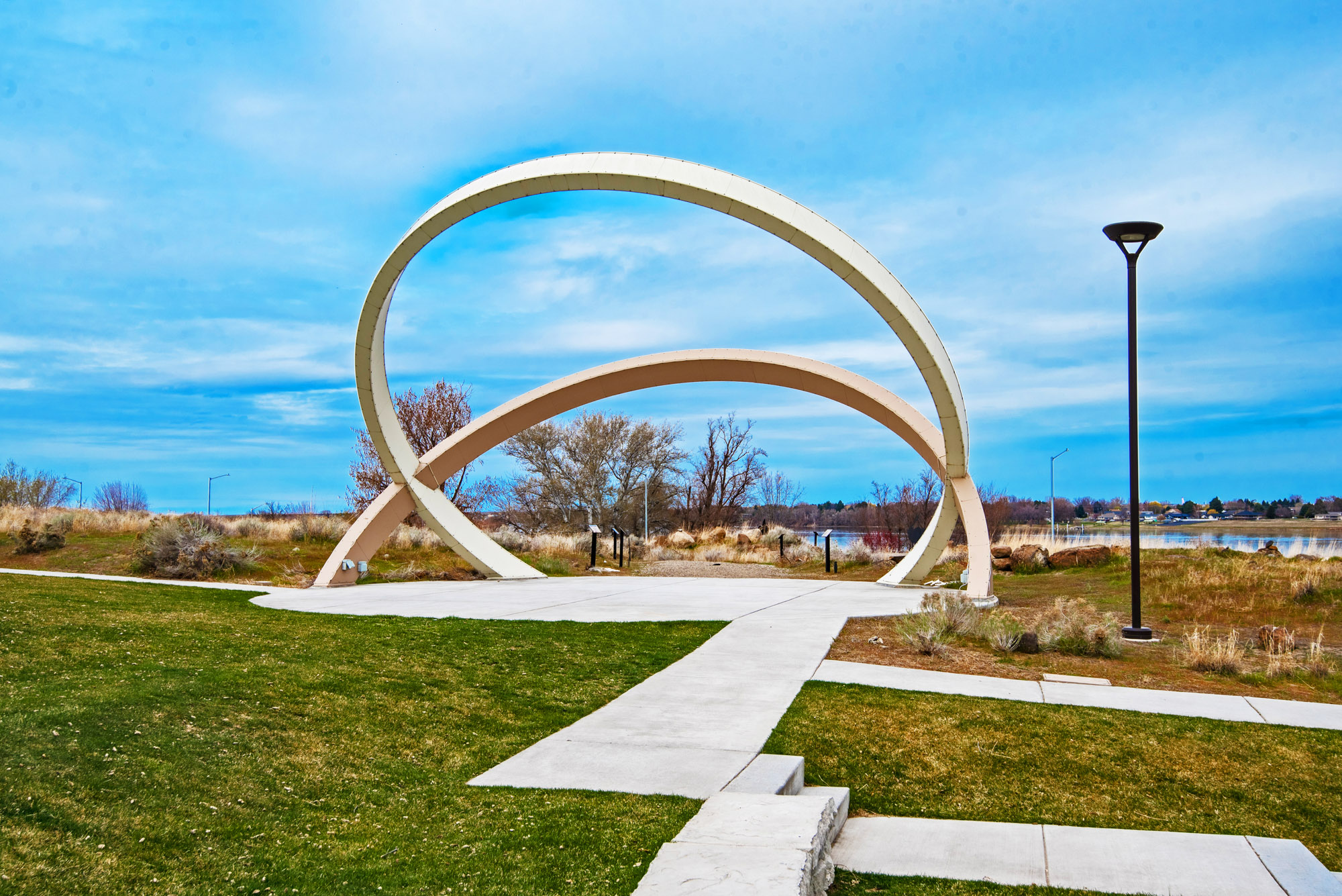 Modern outdoor sculpture with looping arches in park.
