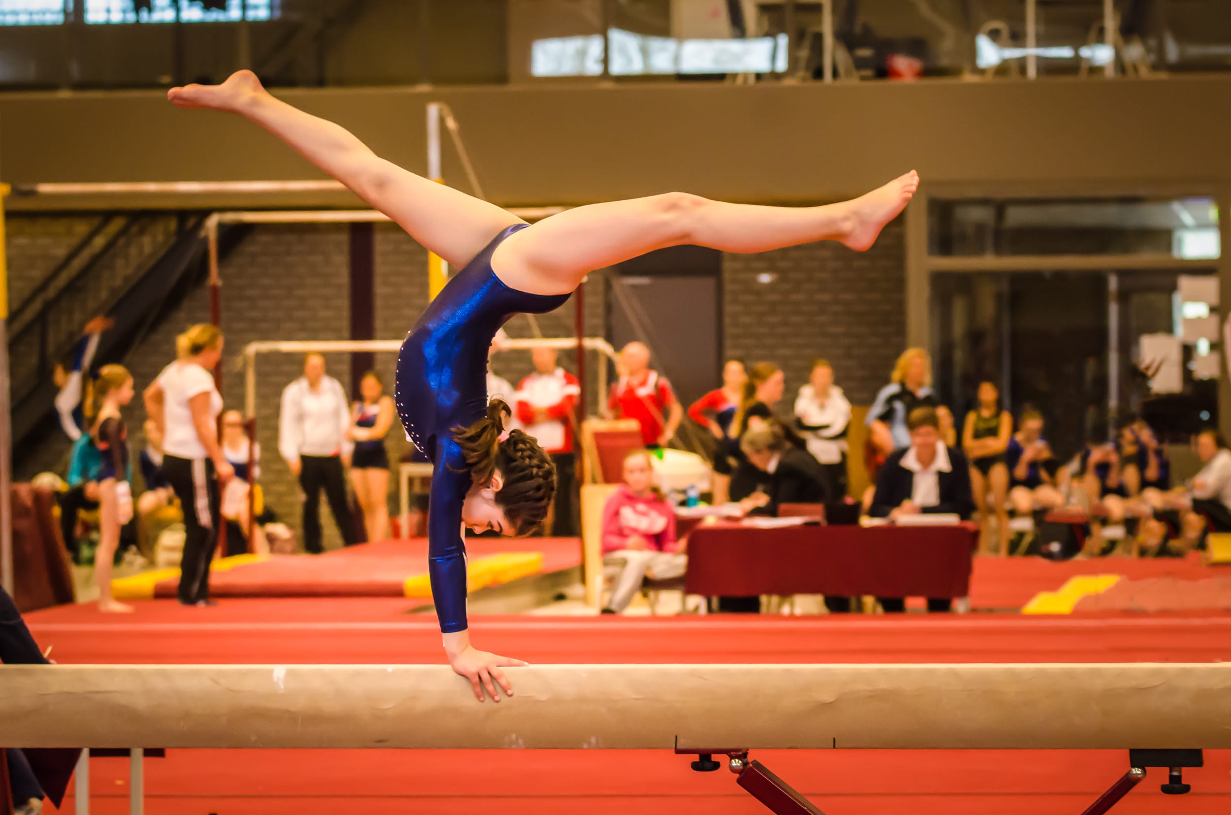 Gymnast performing handstand on balance beam