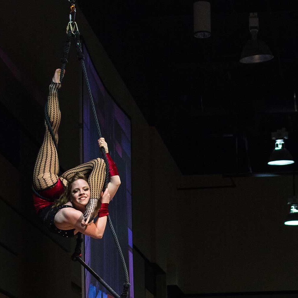 Aerial performer in acrobatic pose on rope
